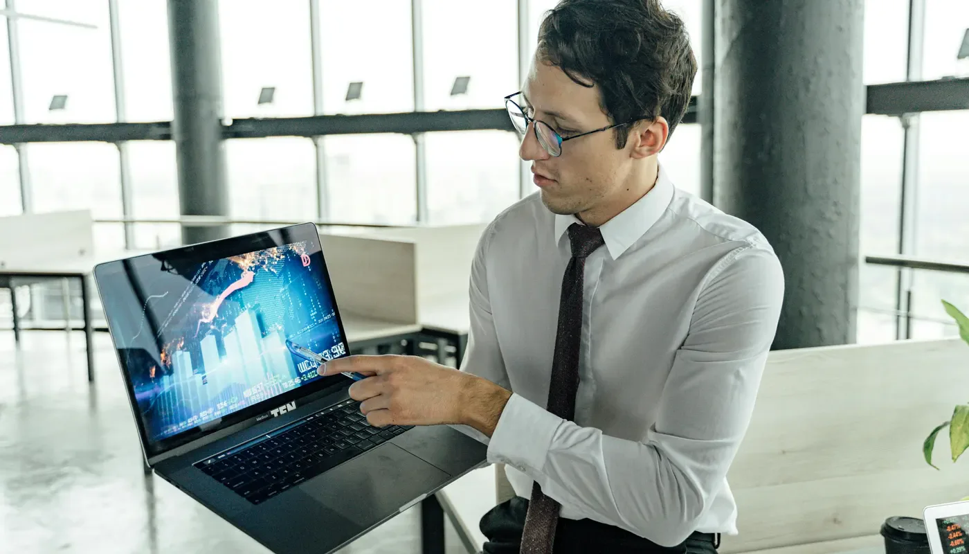 A professional pointing at a laptop during a workflow discussion