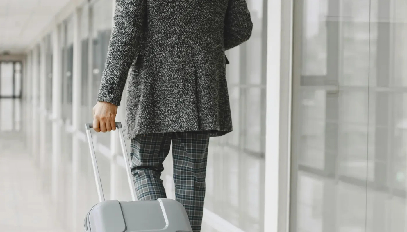 A traveler walking through an airport hallway with luggage